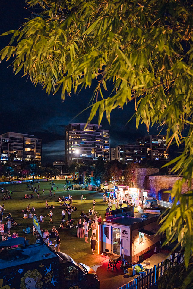 View over Celebration Lawn at night from under a tree looking out at lit food trucks