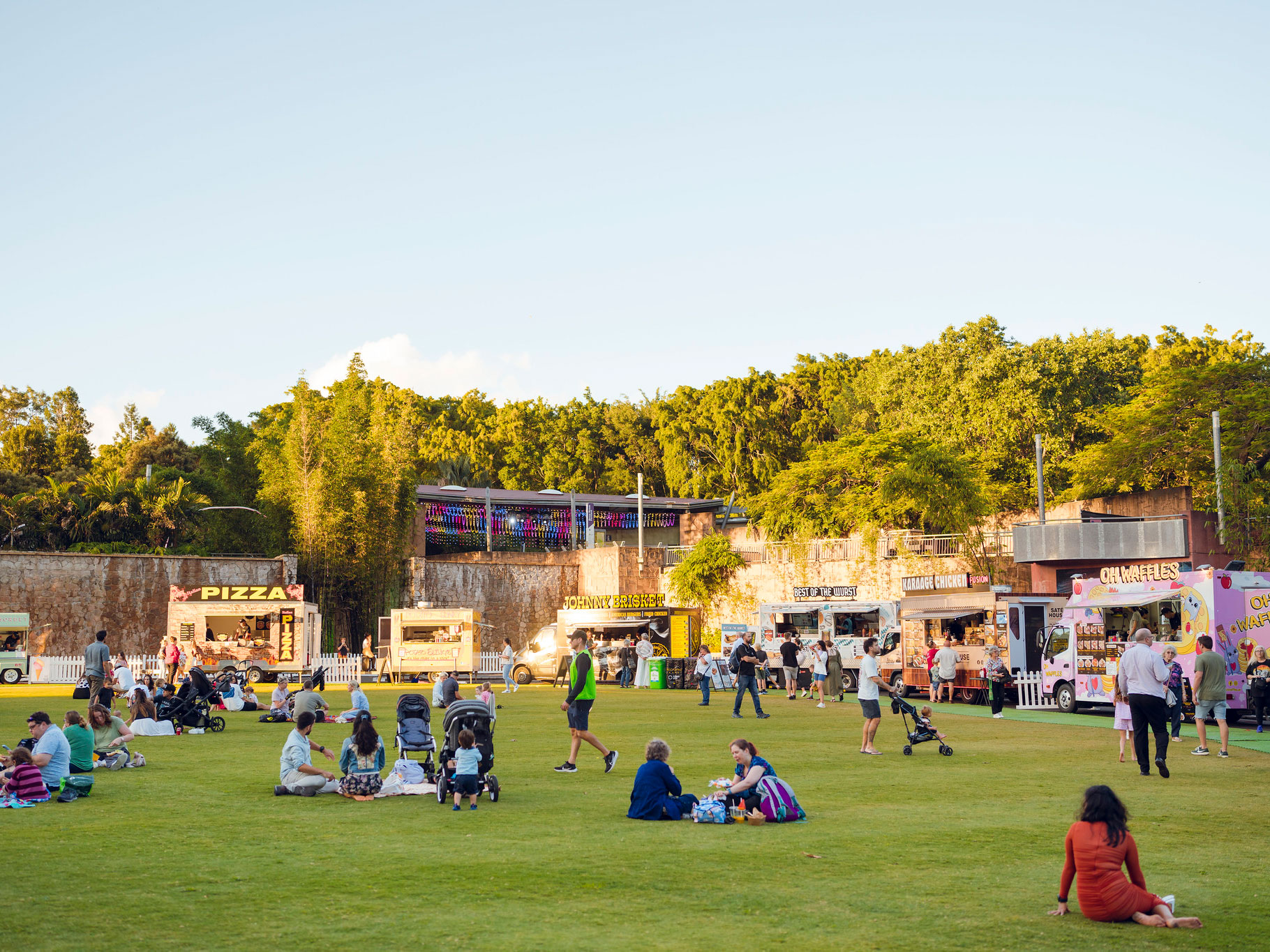 Various food trucks parked on the perimeter of Celebration Lawn with people sat on the lawn
